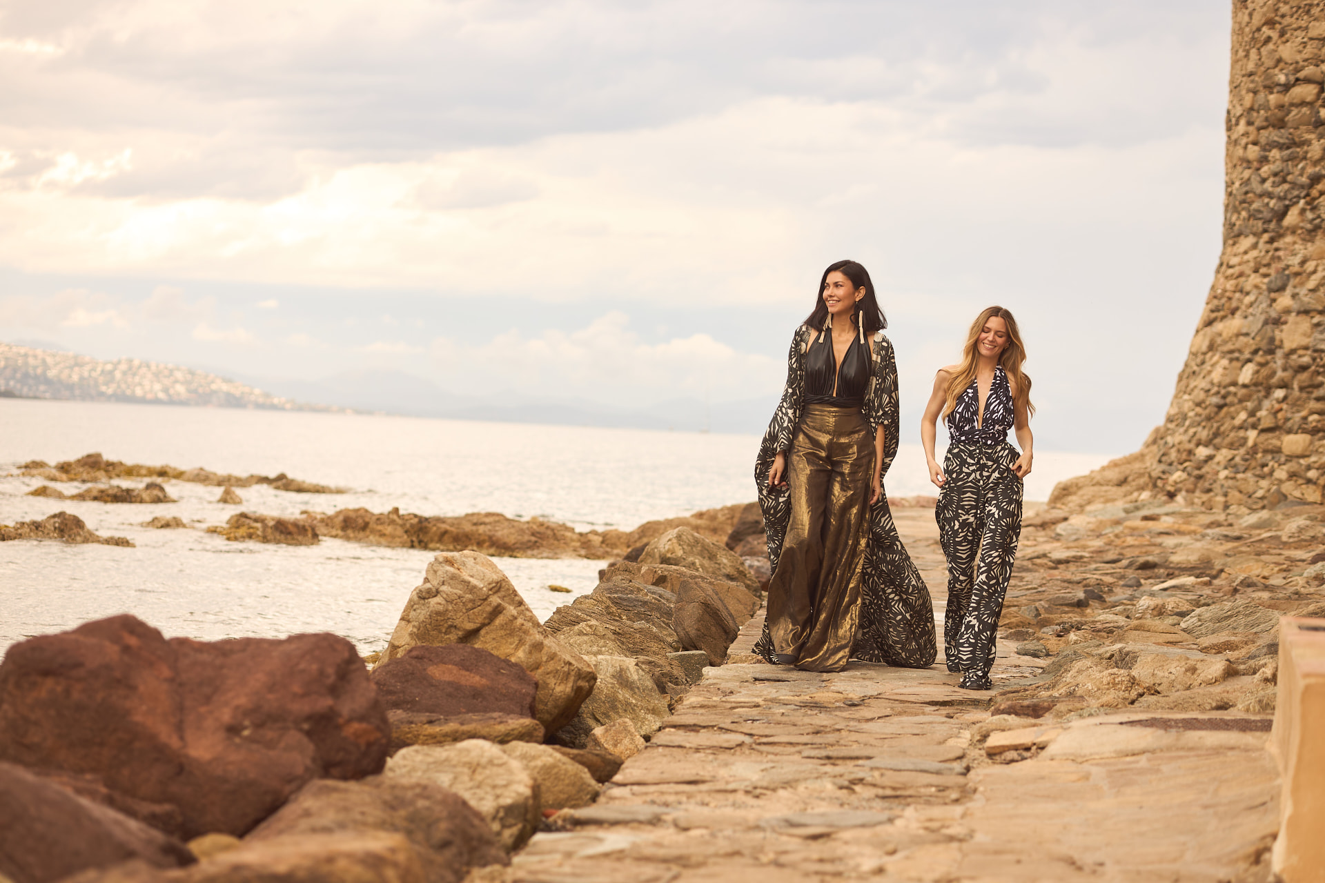 Two women walking a Caribbean shoreline in Anya Privé resortwear